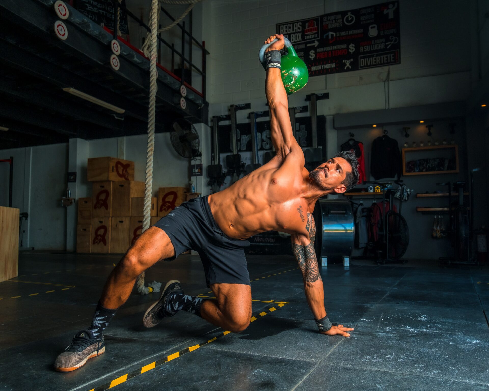 fit guy hold green kettlebell above his head