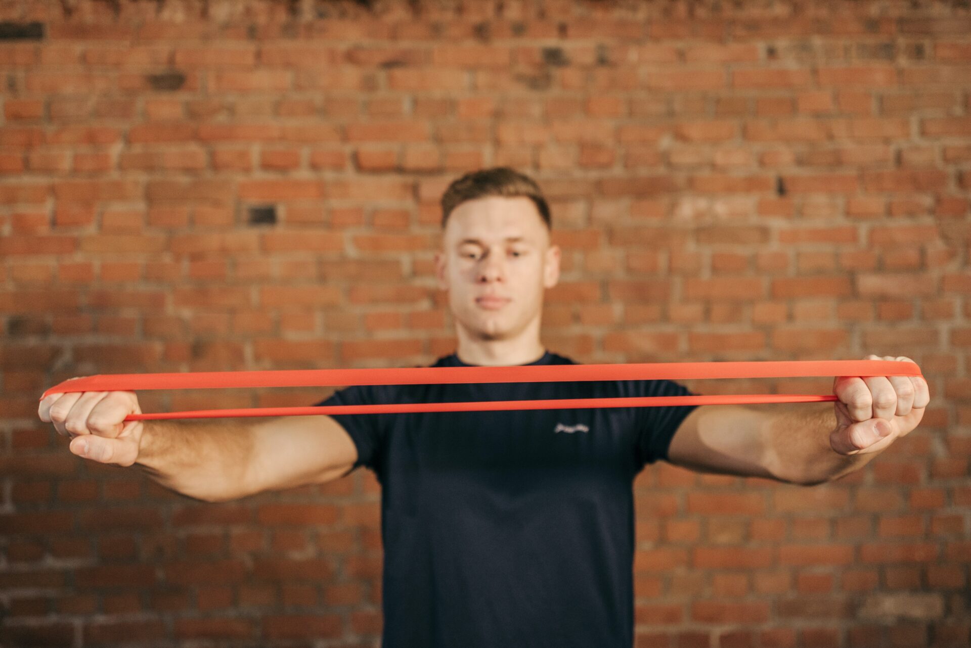 A guy stretching a resistance band between his outstretched arms