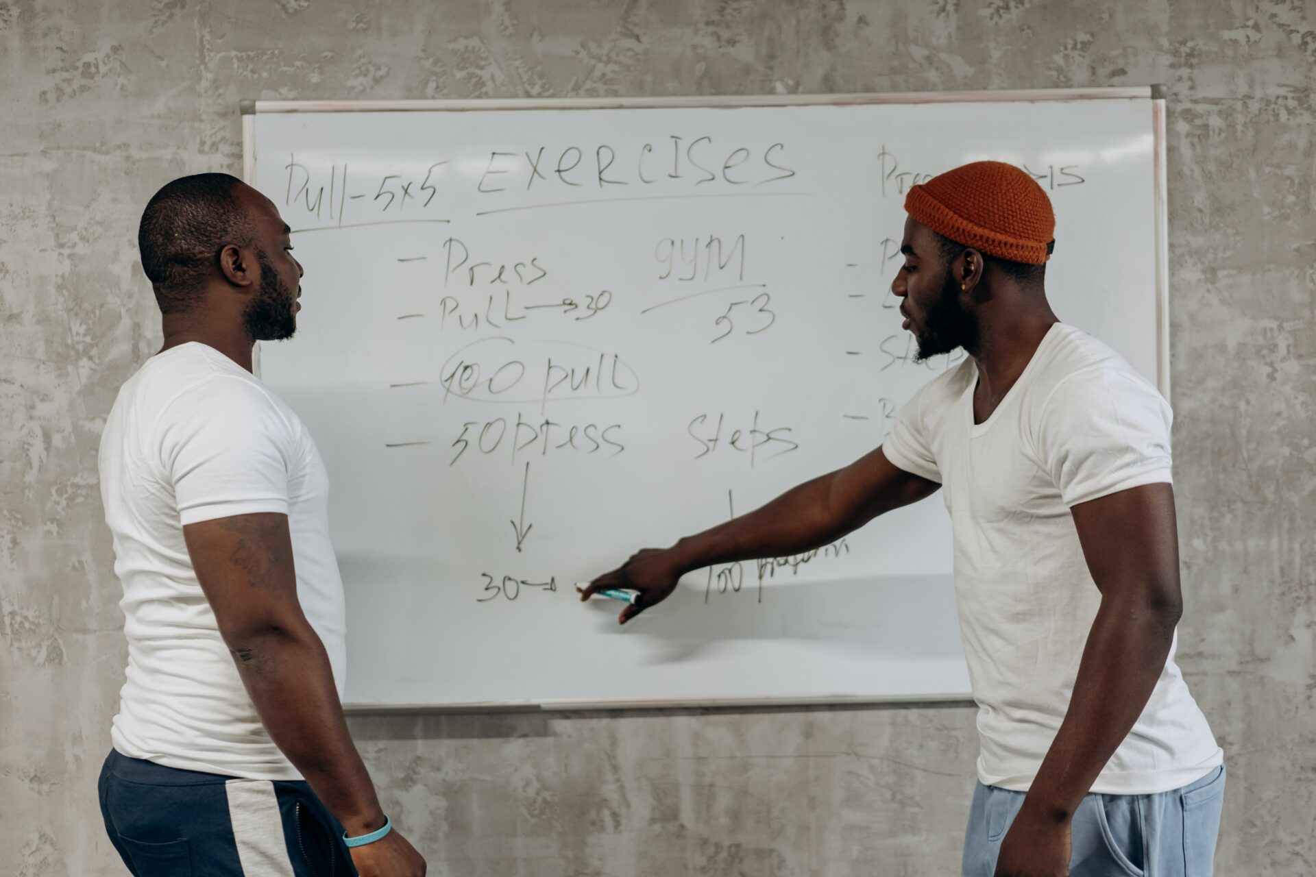 two guys writing up an exercise on a whiteboard