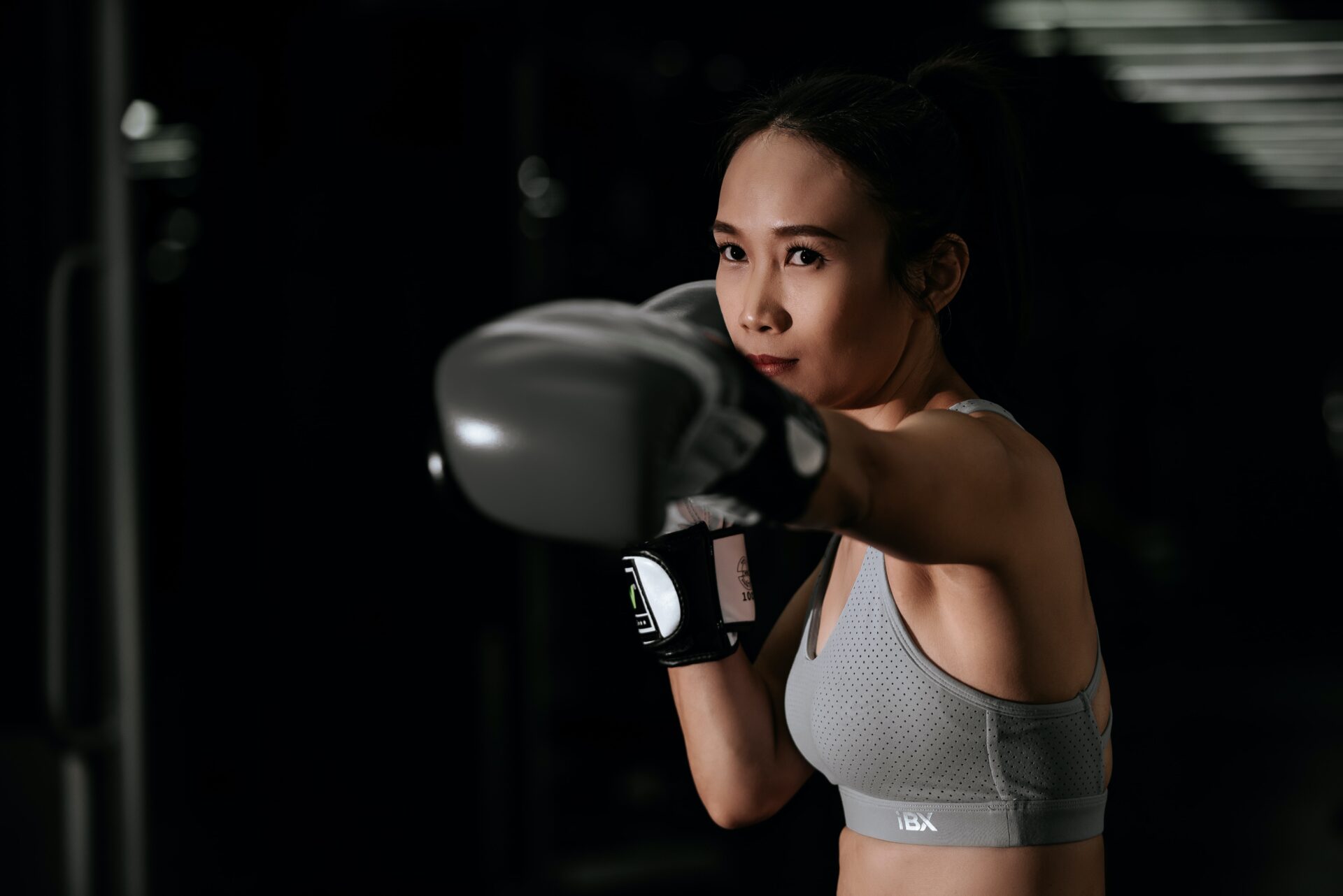 girl punching the air wearing grey gym clothes and black boxing gloves
